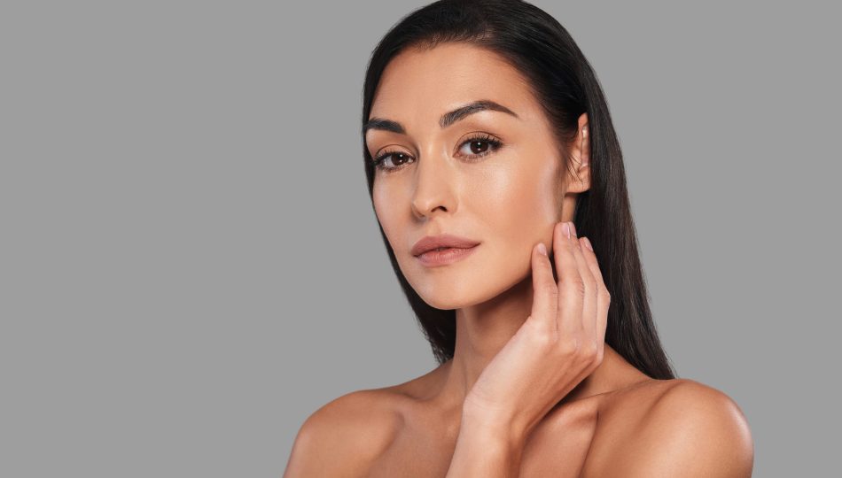 Her confidence shines through. Attractive young woman looking at camera and smiling while standing against grey background